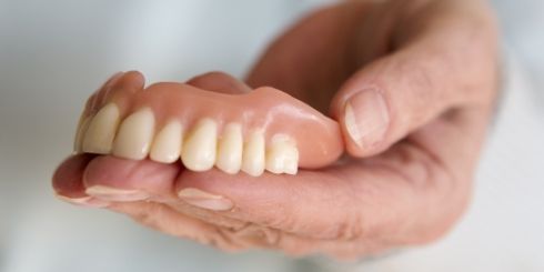 Hand holding a full denture